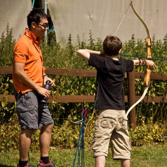 A trainee instructor helping a child during an archery session at Frontier Centre.