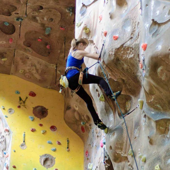 A girl on the 18m climbing wall at Summit Centre, South Wales